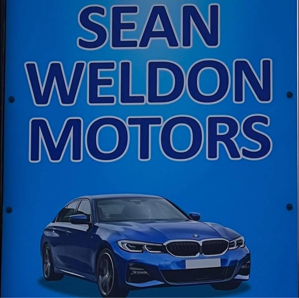 Sean Weldon Motors sign with a blue BMW